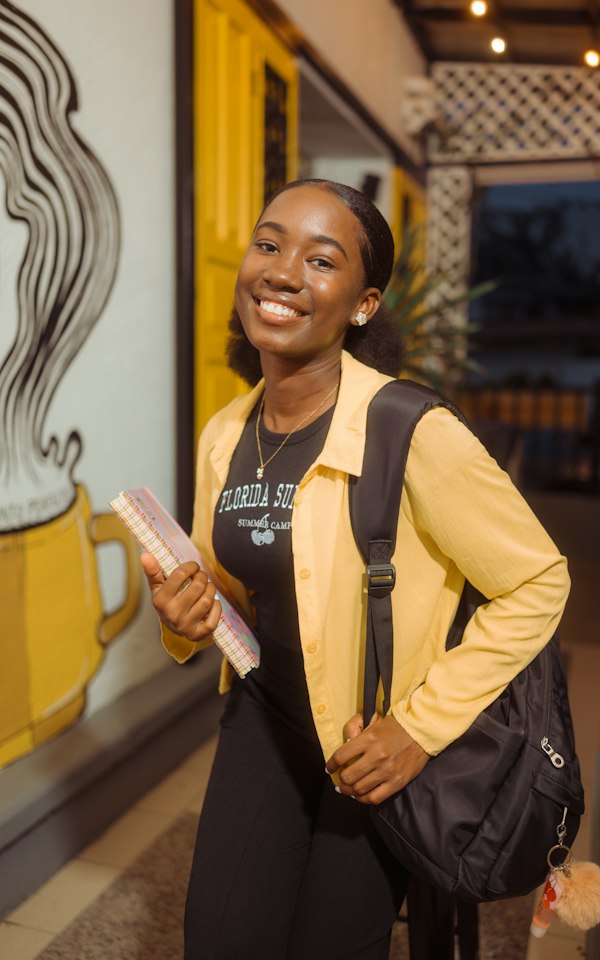 Student with a backpack and notebook smiling