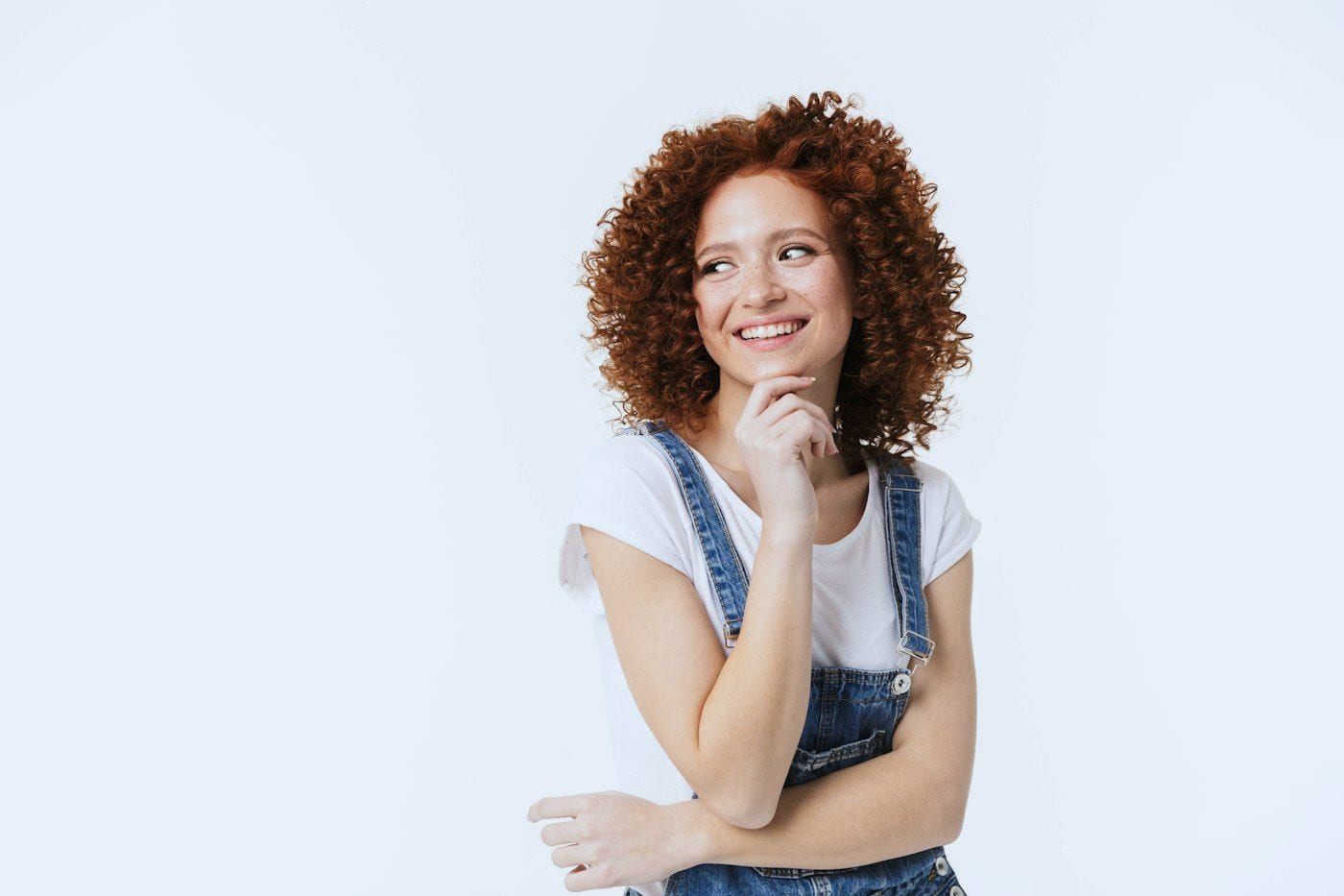 Student in overalls thinking with a hand on her chin