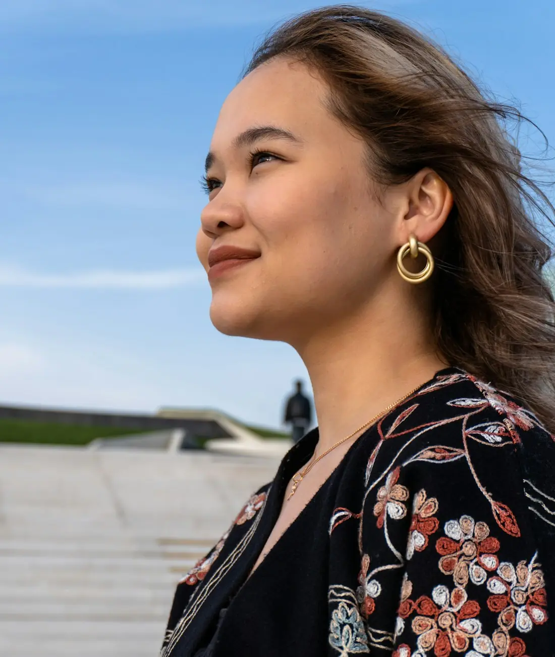 Student smiling and looking up at a blue sky
